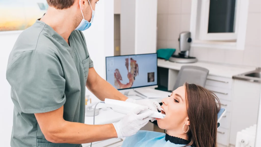 The dentist scans the patient’s teeth using an intraoral scanner